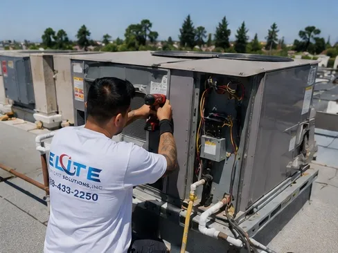 Elite Comfort Solutions technician servicing a rooftop packaged HVAC unit