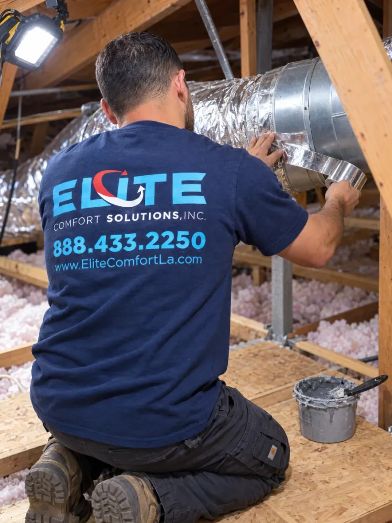 Elite Comfort Solutions technician sealing a flex duct joint with foil tape in a Los Angeles attic