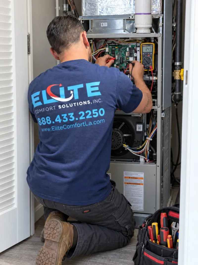 Elite Comfort Solutions technician testing a furnace control board with a multimeter